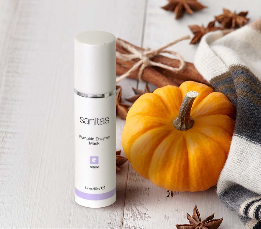 Sanitas pumpkin enzyme mask bottle with a small pumpkin and star anise on a wooden surface