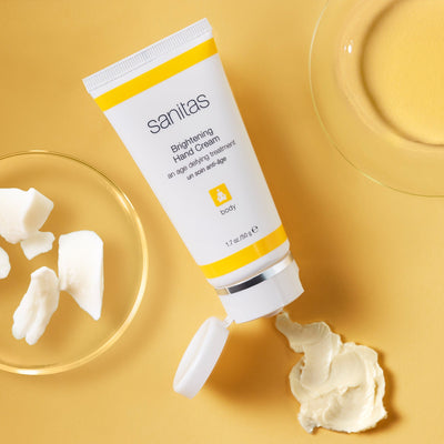 brightening hand cream dispensing on orange table
