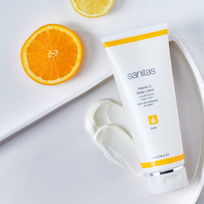 vitamin c body lotion on white table with orange next to it