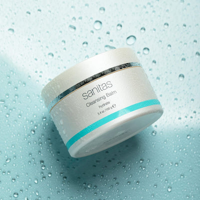 Sanitas Cleansing Balm jar on a water droplet textured blue background