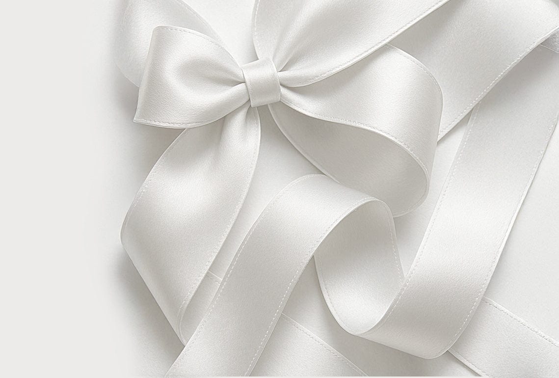 Close-up of a white satin ribbon bow on a light gray background
