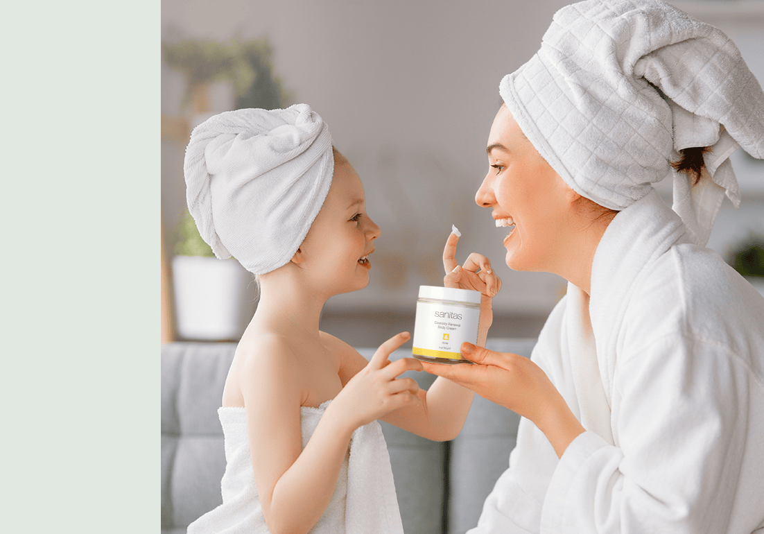 Woman and child with towels on heads holding a jar of Elasticity Renewal Body Cream