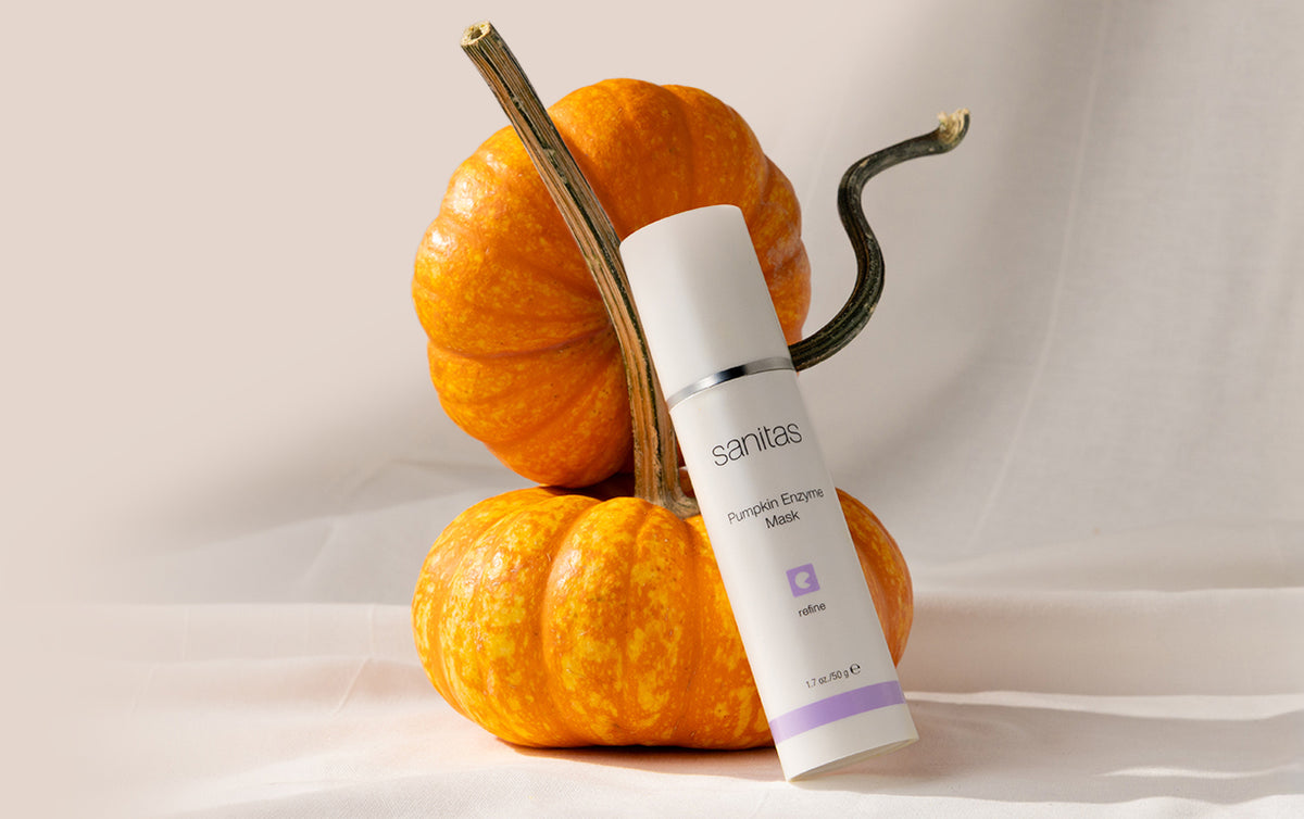 Pumpkin Enzyme Mask 50g bottle laying up against two small orange pumpkin gords