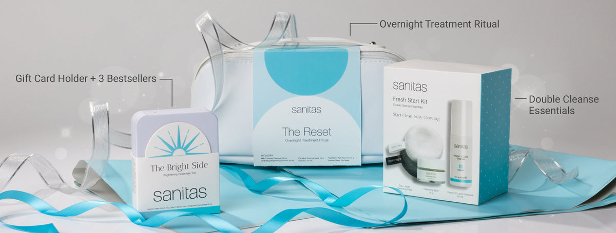 New Holiday Kits set up on blue tissue paper and blue and silver ribbon with text overlay: The Bright Side: Gift Card Holder + 3 Bestsellers, The Rest: Overnight Treatment Ritual, Fresh Start Kit: Double Cleanse Essentials